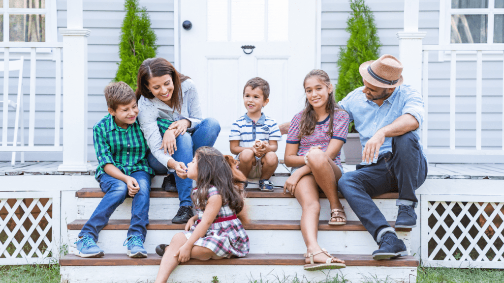 Man, woman and children sitting on the steps in front of a house